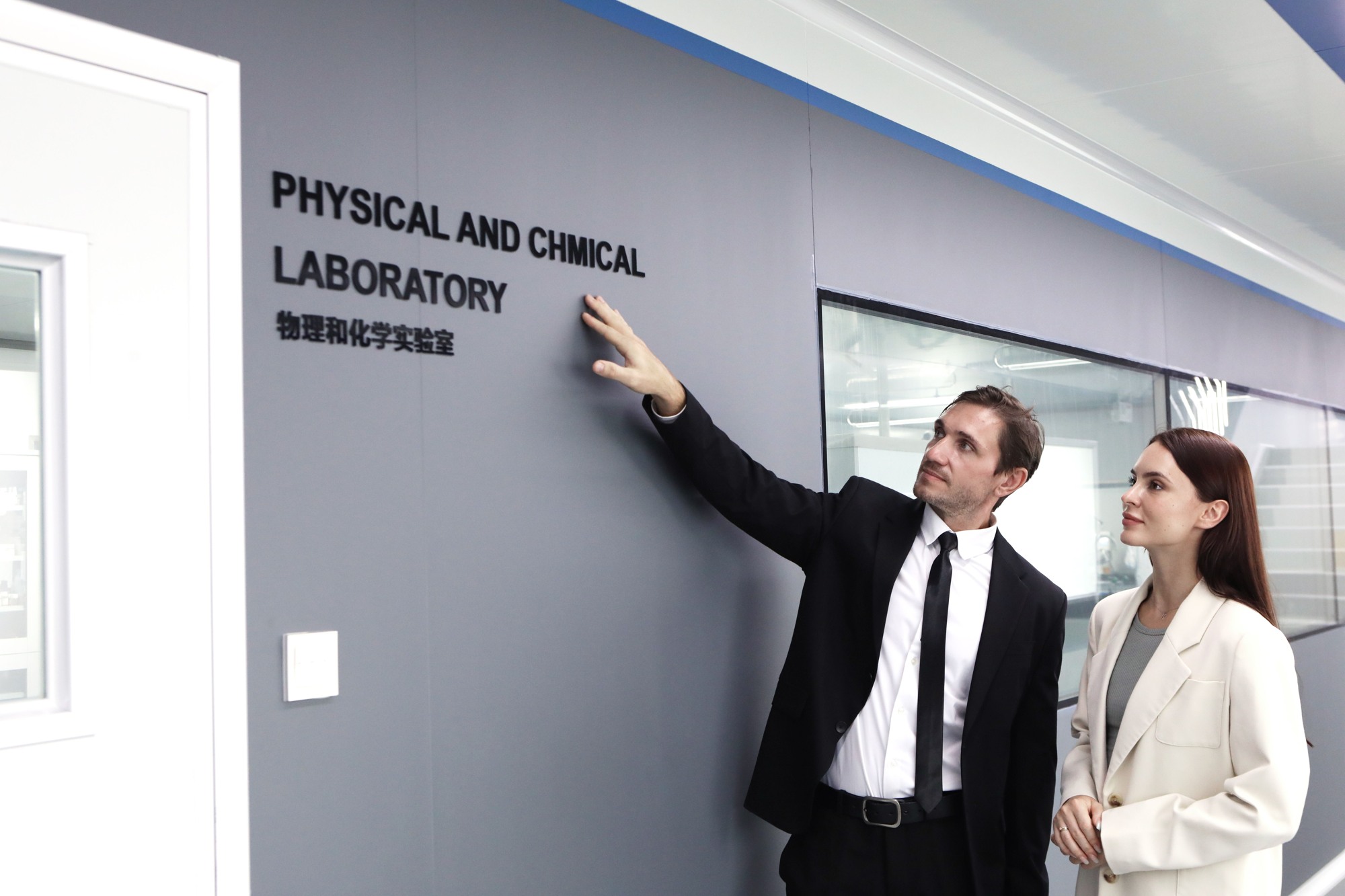 Two visitors outside the physical and chemical laboratory at a cosmetics facility